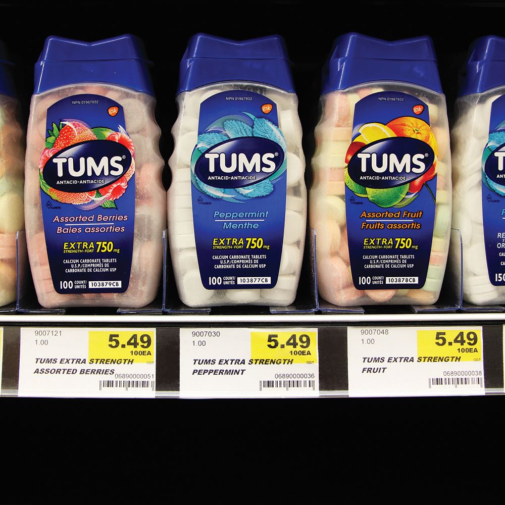 A pharmacy shelf edge front view with bottles of Tums separated by 2-in-1 magnetic dividers.