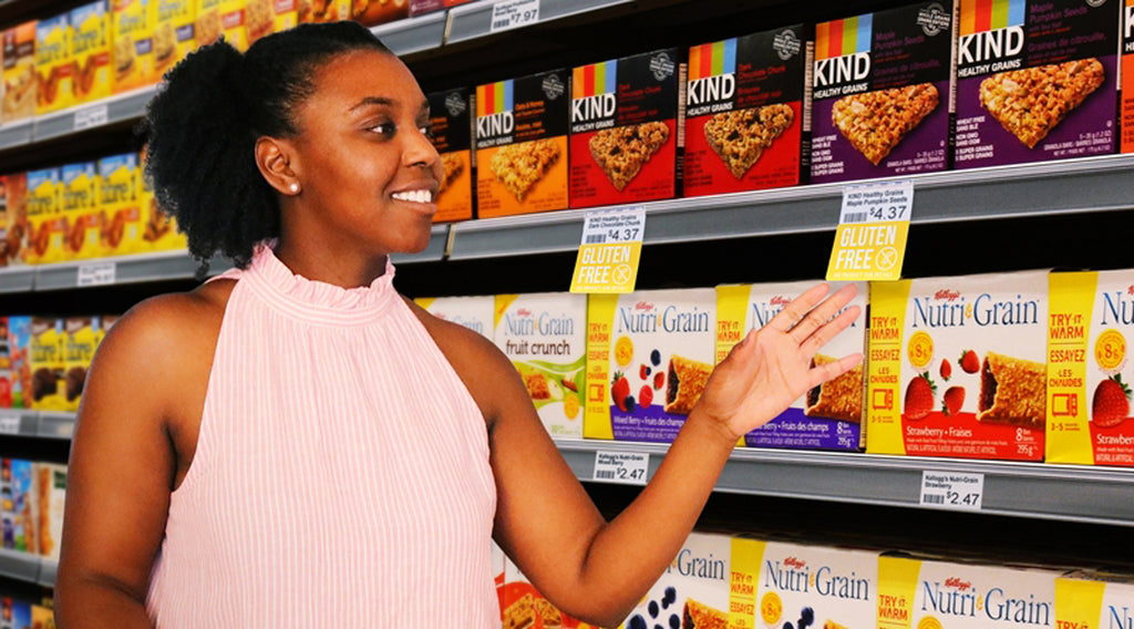 A woman shopping for gulten free products in a granola bar section of a grocery store