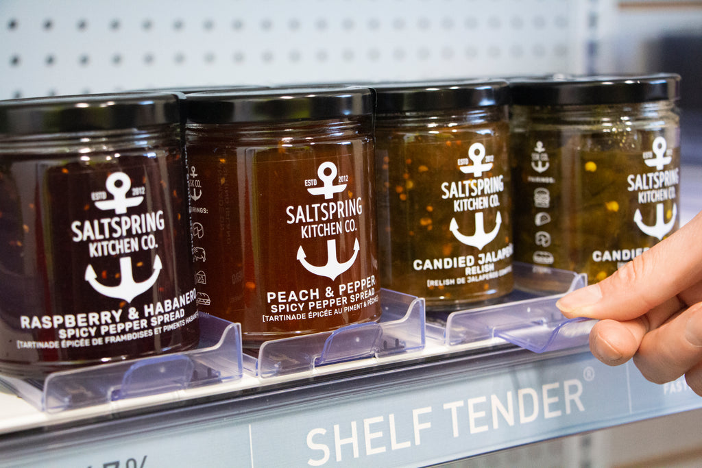 Medium-sized Shelf Tender on a shelf edge holding an assortment of jarred jellies