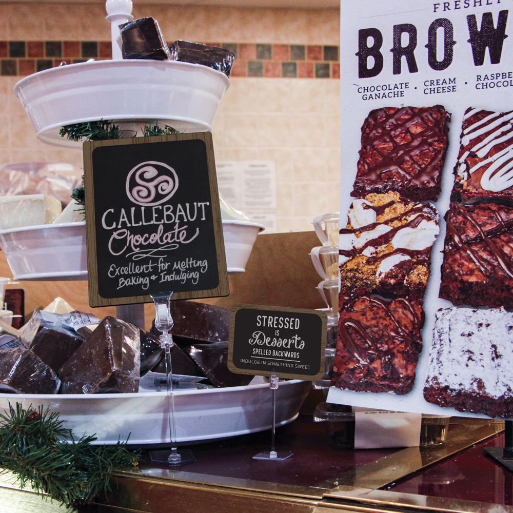 A chocolate display on a bakery counter with TwistKilp sign holders and ChalkTalker deli signs