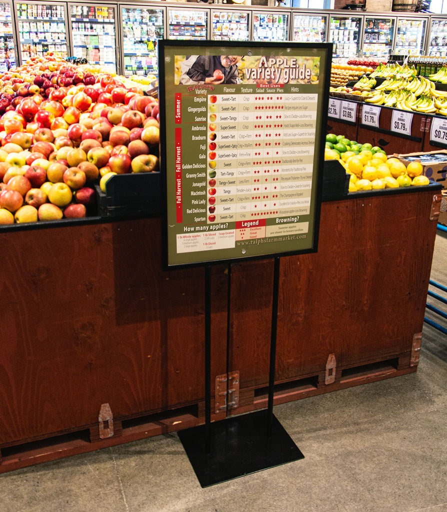 An indoor WalkTalker sign holder in a grocery store produce section.