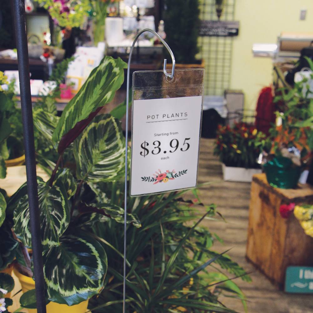 A florist with a variety of plants and a metal hook holding a Vinyl Pouch Sign Holder with a price sign inserted
