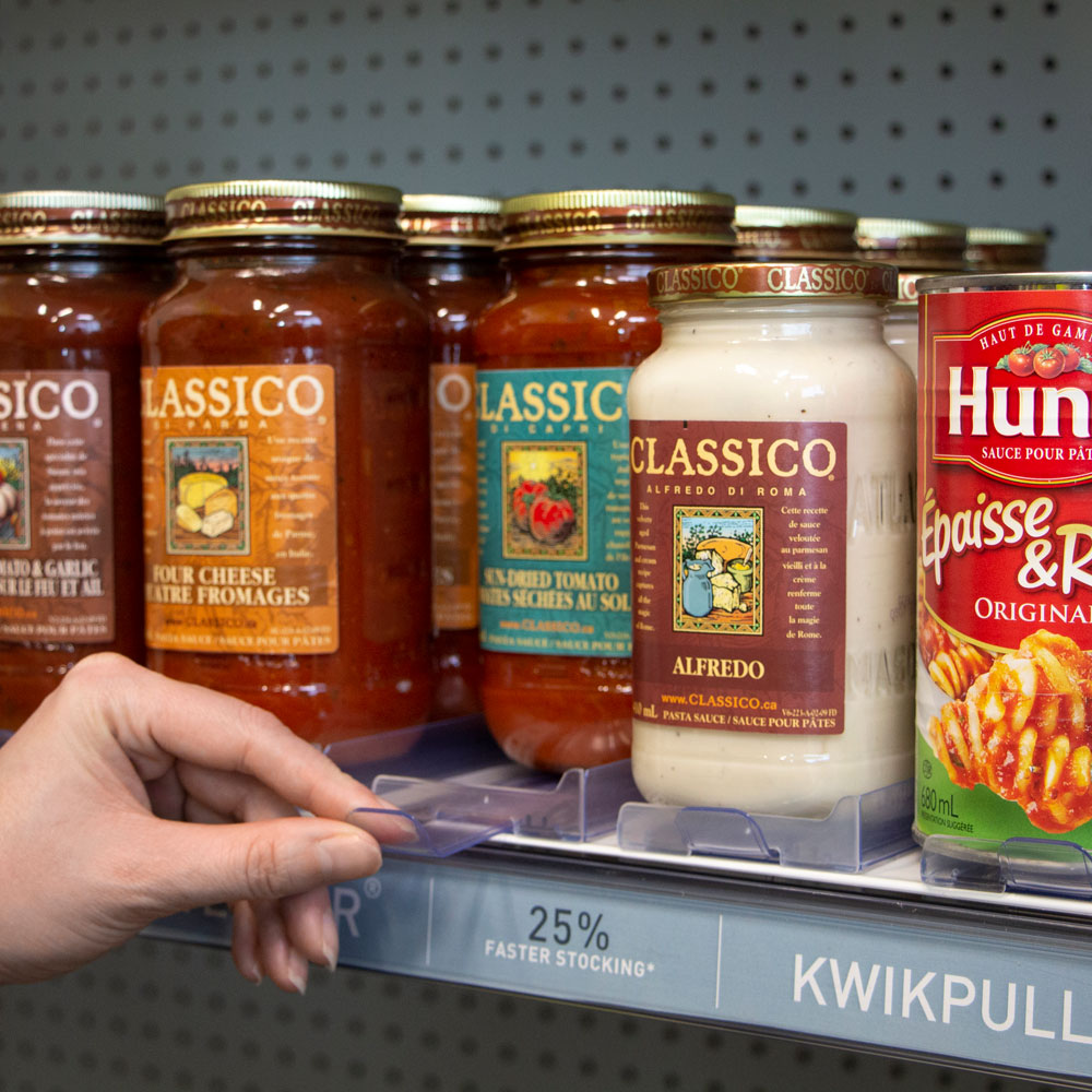 Glass jars of pasta sauces on a medium sized Shelf Tender being pulled forward via the Shelf Tender puller.