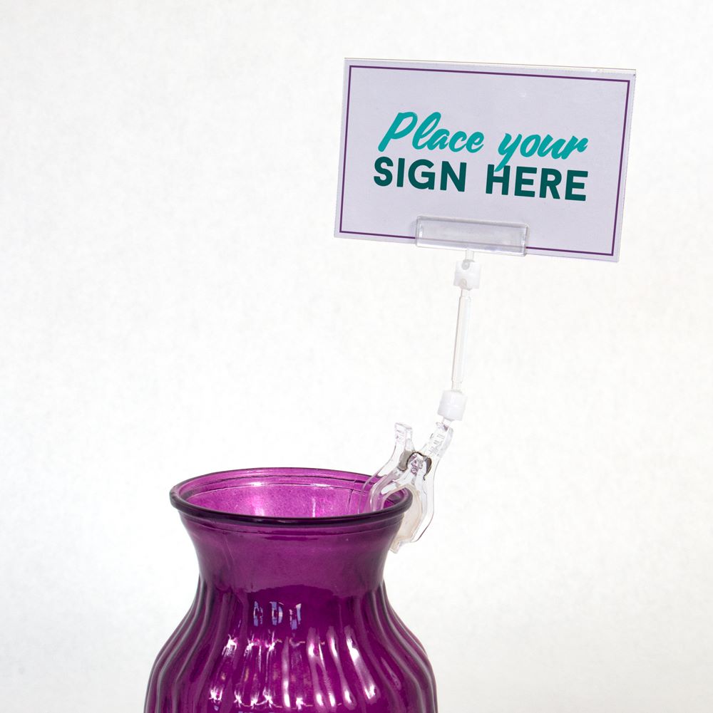 The TwistKlip Card Holder with Large Clip, Short Extension clipped onto a vase and gripping a sign