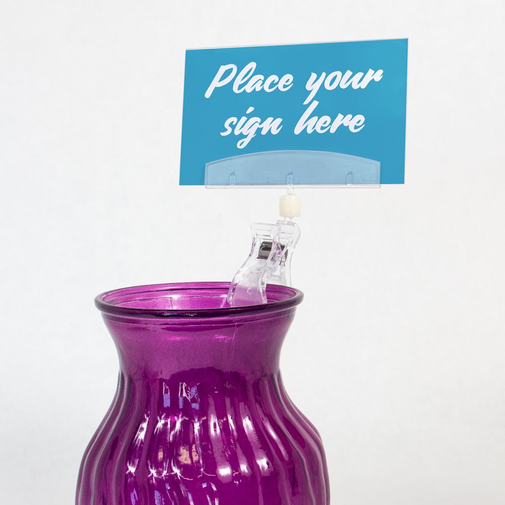 The TwistKlip Sleeve Holder with Large Clip clipped onto a vase and gripping a sign